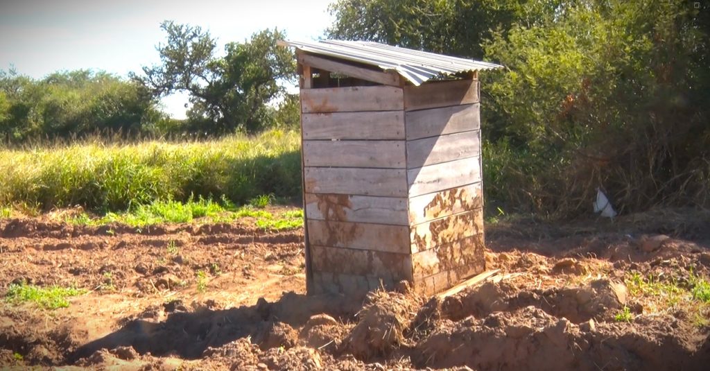En Yalve Sanga, las letrinas de madera persisten aún en escuelas aldeanas mientras aguardan «Letrina Cero»